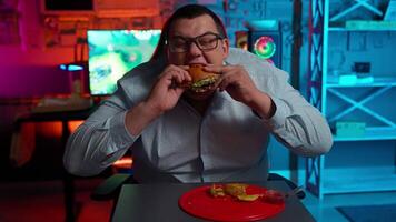 A man eating a burger in front of a computer screen video