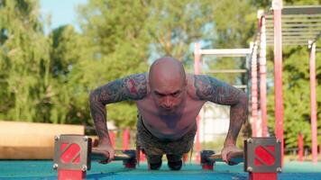 A man with tattoos doing push ups on a bar video