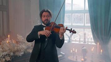 A man in a tuxedo playing the violin in front of candles video