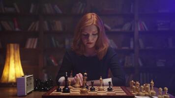 A woman playing chess in front of a bookcase video
