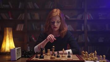 A woman playing chess in front of a bookcase video