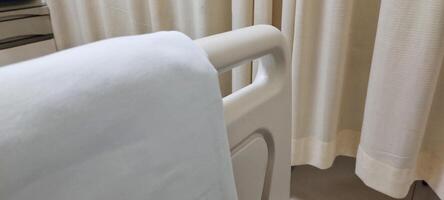 A bed for hospital patients. There are supports made of plastic and aluminum on the edge of the bed, useful as protection so that the patient does not fall out of bed. photo