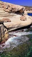 Turquoise waves crashing against the rugged mediterranean coastline under a brilliant sun highlight the essence of summer, showcasing vibrant colors and the calming rhythm of the ocean video