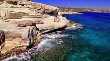 Turquoise waves crashing against the rugged mediterranean coastline under a brilliant sun highlight the essence of summer, showcasing vibrant colors and the calming rhythm of the ocean video