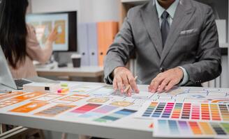 System Developer Analyzing UX UI Plans in Modern Office Setting with Color Swatches and Wireframes photo