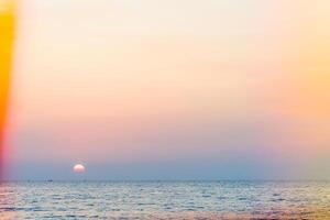 A sunset over the ocean with a colorful umbrella photo