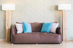 A couch with blue pillows and two lamps photo