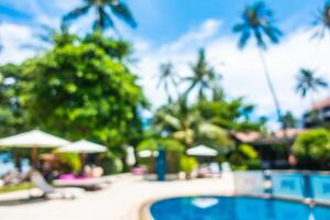 A pool with lounge chairs and umbrellas in front of a resort photo