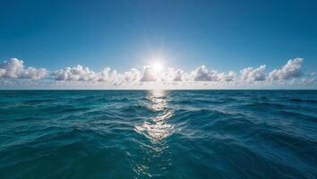 Ocean waves under a vast sky with sun peeking through clouds. photo