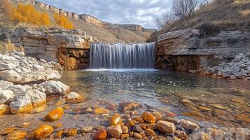 A waterfall flows into a small pool surrounded by rocks photo