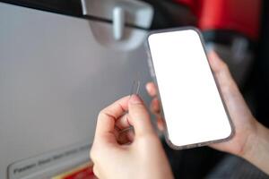 Hand with white blank mobile phone screen mockup with ejector sim card, airplane window background. photo