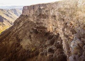 Aerial panning left view Horomayr Monastery monastic complex in the Lori Province of Armenia, Odzun village. Monastery nestled amongst rock and cliff escarpments with caves for protection photo