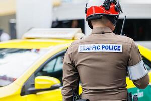 Thai traffic police officer working in busy road in Bangkok city metro operate solve traffic jam problem and public security photo