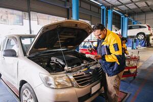 garaje auto mecánico trabajador trabajando cheque motor petróleo nivel palo en coche Servicio centro, indio profesional masculino trabajando foto