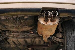 under car exhaust pipe muffler old aged rust rusty closeup auto part service photo
