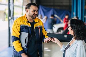 Customer women happy giving car key to mechanic worker for car service fix problem auto center workshop center photo