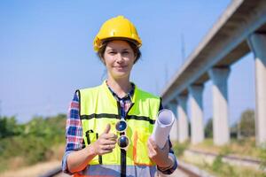 Portrait engineer women on railway tracks construction site with blueprint roll working project manager in suburb transportation line photo