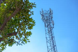 outdoors 5g communication tower digital wireless radio signal long range transmission cell site on blue sky with green tree photo