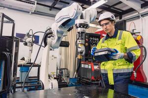 Engineer young man university student learn to control operate industry robot welding arm in robotics engineers lab classroom in polytechnic education. photo