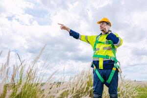 engineer male control operate field working outdoor service maintenance wind power generator. worker hand pointing location to order gesture photo