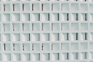 White wall made from concrete with a grid of same size squares and are evenly spaced apart. Pattern background concept. photo