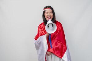 Energetic Asian woman with country flag draped over her shoulder while shouting at a megaphone. photo
