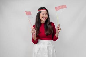 Joyful young Asian woman is holding two flags and smiling, isolated by white background. photo