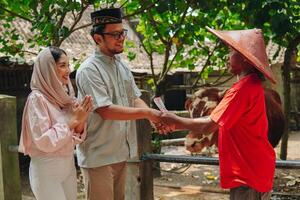 Happy Asian Muslim couple doing handshake with the cattleman buying livestock cows for sacrifices. Eid Al Adha concept. photo