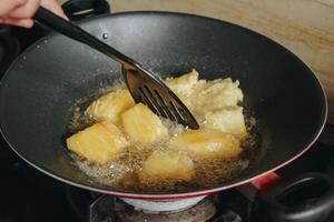 A person is frying cassava slices in a pan. The cassava slices are golden brown and crispy. photo
