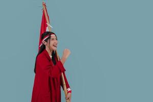 Indonesian woman wearing a red jacket holding a flag while raising fist gesture. photo