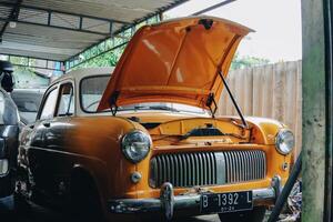 An old orange car with the hood up photo