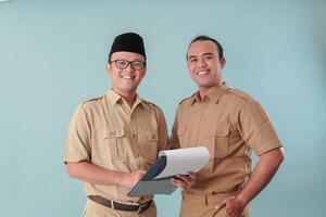 Two government worker men in khaki uniform holding a document report while smiling to the camera. photo