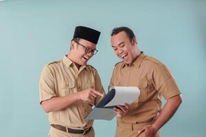 Two men are smiling and pointing at a piece of paper photo