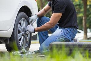 mechanic is preparing the equipment and spare tire to change the tire of the car that had a flat tire during the journey and the mechanic was called by the emergency application of the service center. photo