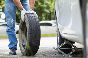 mechanic is preparing the equipment and spare tire to change the tire of the car that had a flat tire during the journey and the mechanic was called by the emergency application of the service center. photo