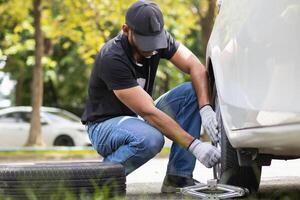 mechanic is preparing the equipment and spare tire to change the tire of the car that had a flat tire during the journey and the mechanic was called by the emergency application of the service center. photo