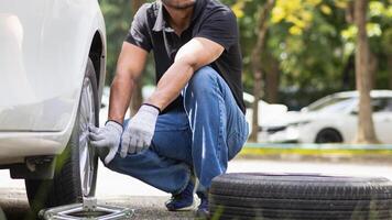 mechanic is preparing the equipment and spare tire to change the tire of the car that had a flat tire during the journey and the mechanic was called by the emergency application of the service center. photo