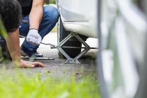 mechanic is preparing the equipment and spare tire to change the tire of the car that had a flat tire during the journey and the mechanic was called by the emergency application of the service center. photo