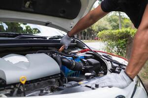 mechanic from the service center is helping to jump start the car battery for customer who has a deteriorated battery and cannot start the car. Jump starting the battery helps to continue the journey photo