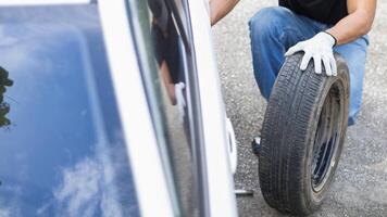 mechanic is preparing the equipment and spare tire to change the tire of the car that had a flat tire during the journey and the mechanic was called by the emergency application of the service center. photo