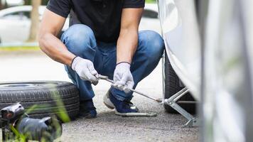 mechanic is preparing the equipment and spare tire to change the tire of the car that had a flat tire during the journey and the mechanic was called by the emergency application of the service center. photo