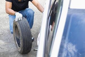 mechanic is preparing the equipment and spare tire to change the tire of the car that had a flat tire during the journey and the mechanic was called by the emergency application of the service center. photo