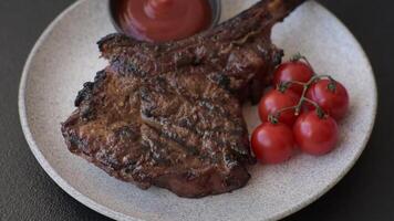 Grilled wagyu beef tomahawk steak with salt, spices and herbs on a dark concrete background video