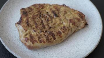 Grilled beef or pork steak with salt, spices and herbs on a dark concrete background video