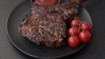 Grilled wagyu beef tomahawk steak with salt, spices and herbs on a dark concrete background video