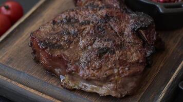 Grilled wagyu beef tomahawk steak with salt, spices and herbs on a dark concrete background video