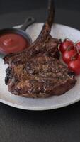 Grilled wagyu beef tomahawk steak with salt, spices and herbs on a dark concrete background video