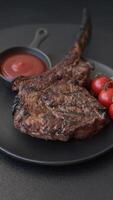 Grilled wagyu beef tomahawk steak with salt, spices and herbs on a dark concrete background video