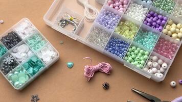 Crafting with colorful beads on a flat workspace with tools and containers in bright daylight video