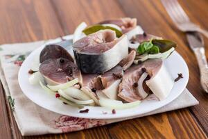lightly salted mackerel with onions and spices on a wooden table photo